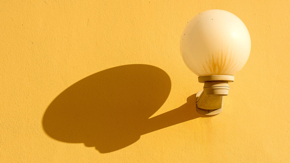 Applique murale globe en verre projetant son ombre sur un mur jaune