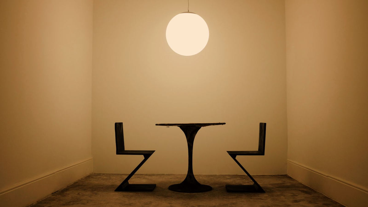 Suspension boule en verre opalin au-dessus d'une petite table ronde