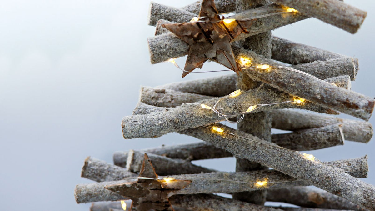 Sapin de Noël en branches de bois orné de guirlandes lumineuses