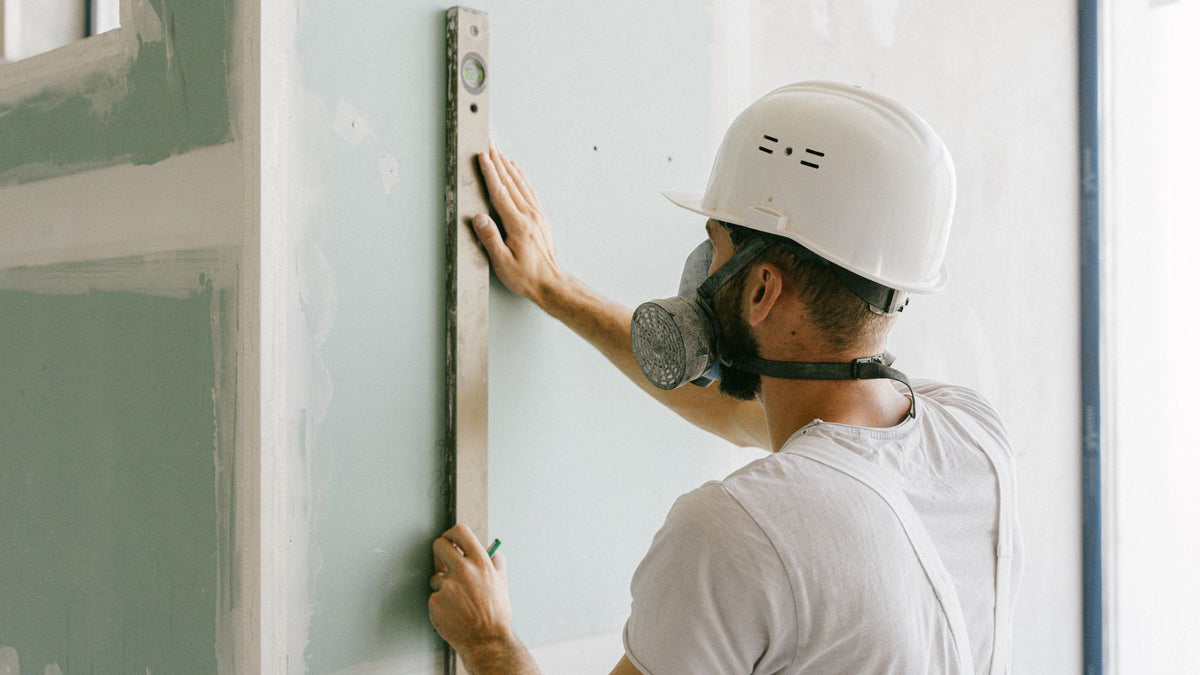 Artisan vérifiant un mur au niveau avant de fixer une applique dans le placo
