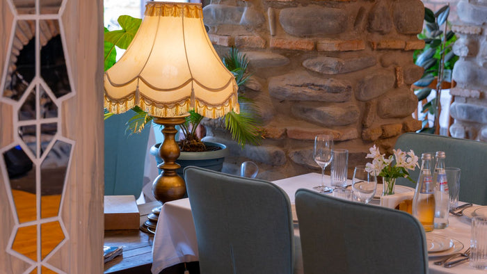 Salle à manger élégante avec lampe vintage devant un mur en pierre naturelle