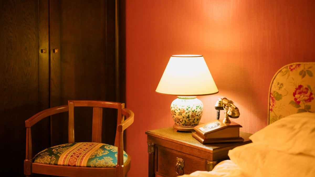 Lampe ancienne rénovée allumée sur une table près d'un fauteuil