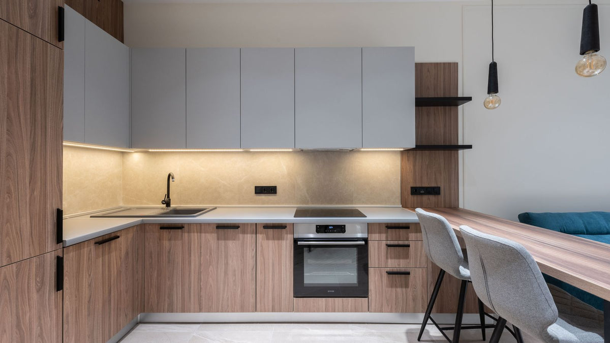 Cuisine moderne aux tons gris éclairée par une suspension en béton