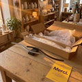 Applique vague noire de 60 cm posée sur une table de boutique, à côté de son carton et de la carte Merci #noir
